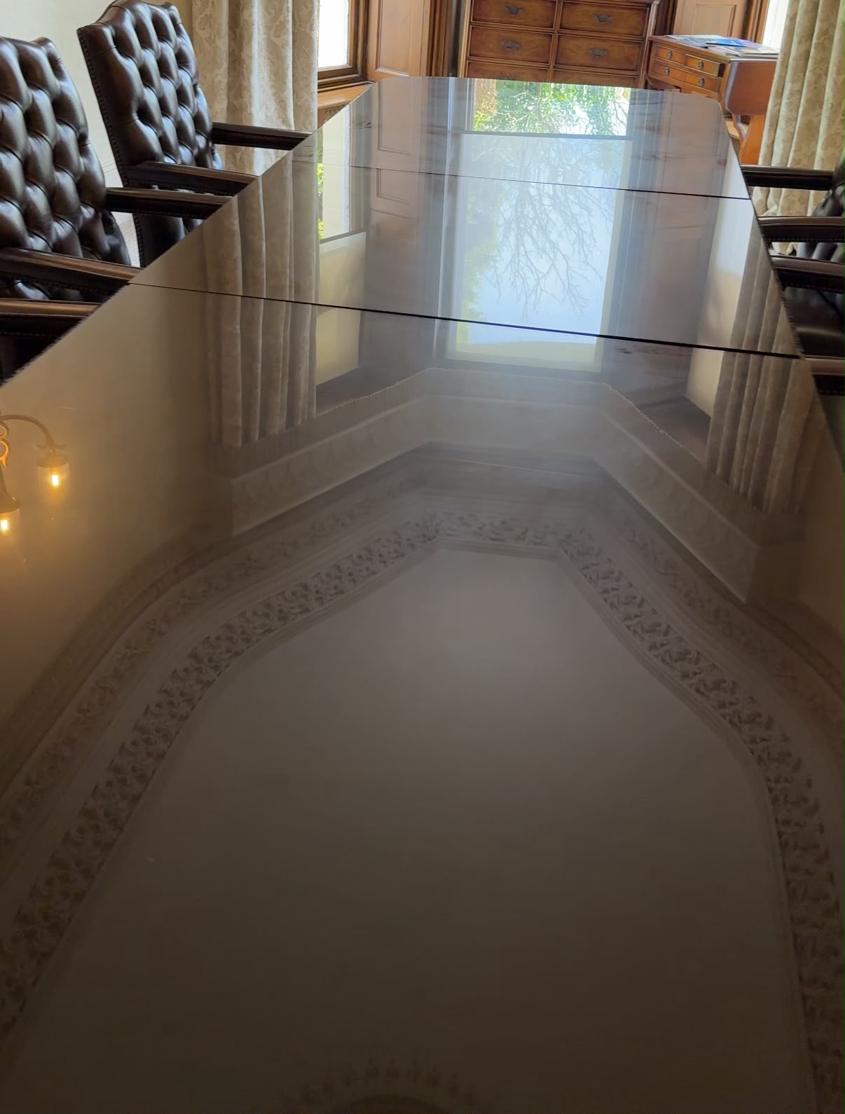The polished boardroom table reflecting the room's period ceiling